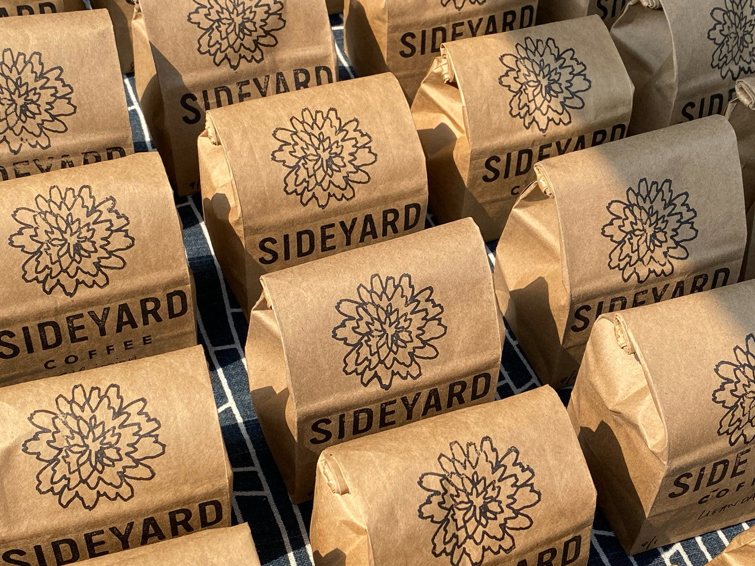 rows of coffee bags, stamped with the Sideyard coffee logo, arranged in a grid and seen from above